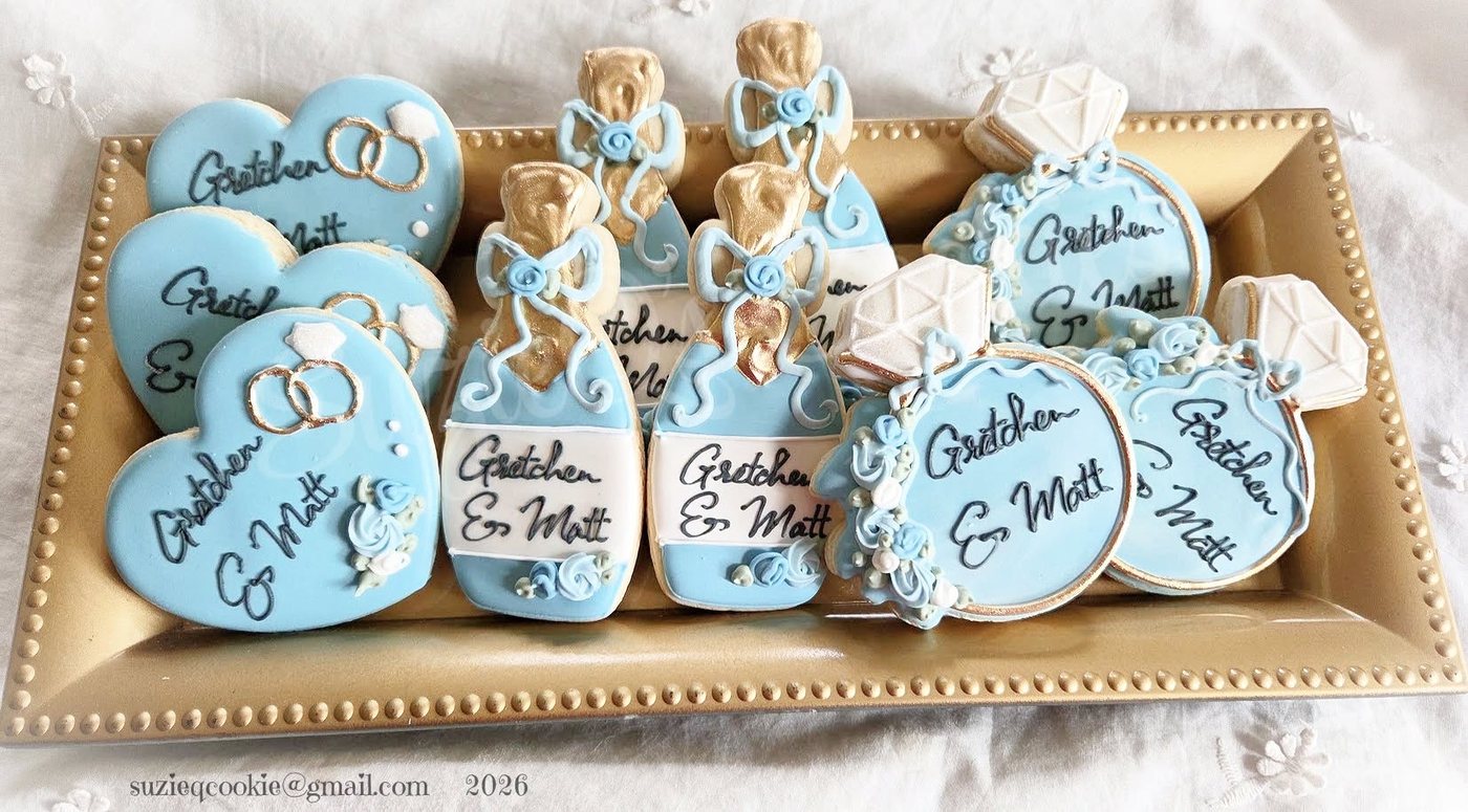 Powder-blue wedding cookies with gowns, rings and names on a gold tray